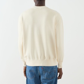 Model wearing Levi's cream garment-dyed sweatshirt, back view, styled with blue jeans