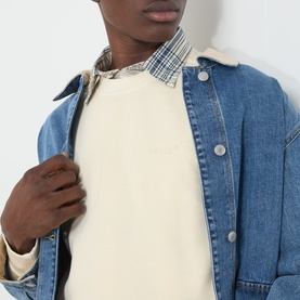 Model wearing Levi's Garment Dye Rutabaga cream sweatshirt, styled with a blue denim jacket and checked shirt underneath.