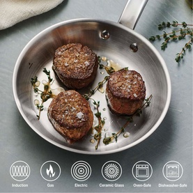 Tramontina silver stainless steel frying pan with seared meat and herbs, showing induction, gas, electric, ceramic, oven-safe and dishwasher-safe