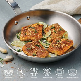 Tramontina silver stainless steel frying pan with seasoned fish fillets, lime slices and herbs, showing compatibility icons below