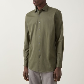 Model wearing Rodd & Gunn Ascot Park Shirt in khaki, featuring pointed collar, button fastening, and long sleeves, styled with light grey trousers.