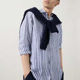 Model wearing Rodd & Gunn Seadown Stripe Shirt in French navy, linen, with classic collar and long sleeves, styled with a navy knitwear tied at neck.