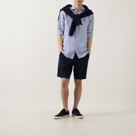 Model wearing Rodd & Gunn Seadown Stripe Shirt in French navy, styled with navy shorts and canvas shoes, navy knit tied over shoulders.