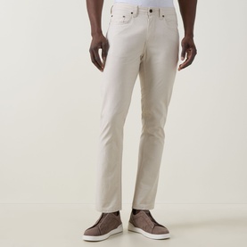 Model wearing Rodd & Gunn Gunn Straight-Leg Jeans in beige with five-pocket styling, tonal stitching, styled with brown suede trainers.