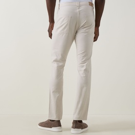 Model wearing Rodd & Gunn Gunn Straight-Leg Jeans in beige, rear view, styled with taupe slip-on shoes.