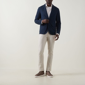 Model wearing Rodd & Gunn Gunn Straight-Leg Jeans in beige, styled with a navy blazer and brown suede shoes.