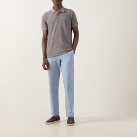 Model wearing Rodd & Gunn The Gunn Polo Shirt in Mocha with light blue trousers and dark suede trainers.