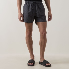Model wearing Hugo black swim shorts with textured stripe pattern, styled with black slides