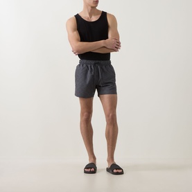 Model wearing Hugo black polyester swim shorts with elasticated waist, styled with a black vest and dark slider sandals