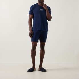 Model wearing Hugo Laze Logo Lounge Shorts in navy, styled with matching navy T-shirt and slippers
