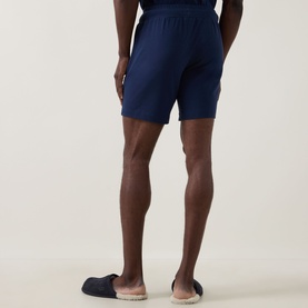 Model wearing Hugo Laze Logo Lounge Shorts in navy, rear view, styled with navy slip-on shoes, elasticated waist visible