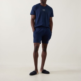 Model wearing Hugo Laze Logo Lounge T-Shirt in navy, styled with matching navy lounge shorts and dark slippers.