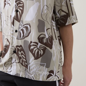 Model wearing Hugo light beige short-sleeve shirt with brown and grey tropical leaf print, button-front, relaxed fit