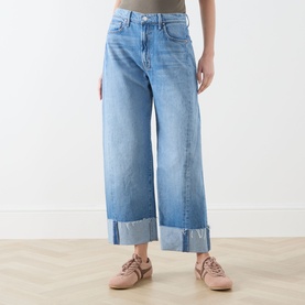Model wearing Mother Straight Jeans in Last Bite light blue wash, wide-leg with deep turn-up cuffs, styled with pink trainers.
