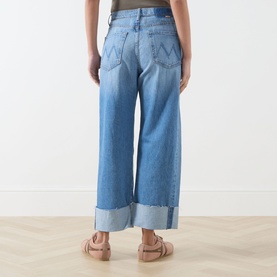 Model wearing Mother straight-leg jeans in Last Bite light blue denim with wide cuffed hem, rear view, styled with nude flat sandals