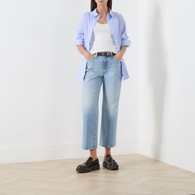 Model wearing Mother straight-leg jeans in Reelin In The Fun light wash denim, styled with a blue shirt, white vest and black loafers
