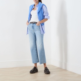 Model wearing Mother straight jeans in Reelin In The Fun light wash denim, styled with a blue oversized shirt, white top, and black loafers.