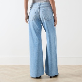 Model wearing Mother Wide Leg jeans in light blue, rear view showing wide-leg silhouette, back pockets, and full-length hem.