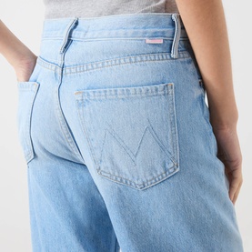 Model wearing Mother Wide Leg jeans in blue, close-up of back pocket with signature M-stitch detail, light wash denim