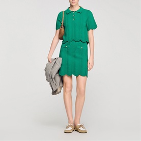 Model wearing Sandro Scallop Trim Knitted Skirt in emerald green with matching polo top, styled with gold loafers and tan bag.