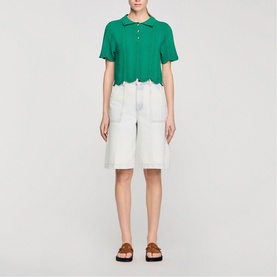 Model wearing Sandro Scallop Trim Knitted Top in emerald green with white denim shorts and brown flat sandals.