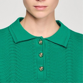 Model wearing Sandro Scallop Trim Knitted Top in emerald green, showing polo collar and gold lion-head buttons at neckline.