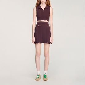 Model wearing Sandro Wave Cropped Knit Top in brown with buttoned polo collar, styled with matching shorts and green trainers.