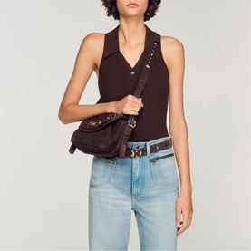 Model carrying Sandro Le Mambo Janys Studded Suede Bag in black brown, worn crossbody with adjustable studded strap, styled with brown top and jeans.