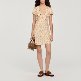 Model wearing Sandro Floral Ruffle Mini Dress in light pink with V-neckline and ruffled bust, styled with brown suede sandals and mini bag.