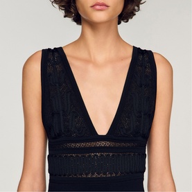 Model wearing Sandro Embroidered Hybrid Dress in black, featuring deep V-neckline, lace embroidery and fringe trim detail at waist.