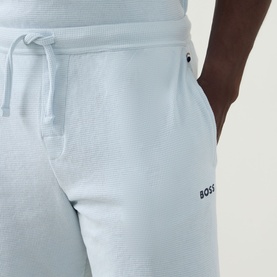 Model wearing Hugo Boss Logo Waffle Texture Drawstring Lounge Shorts in light blue, showing drawstring waist, side pocket and logo detail.