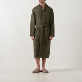 Model wearing Hugo Boss Logo Waffle Robe in green, shawl lapel, self-tie belt, mid-length, styled with taupe slip-on shoes.