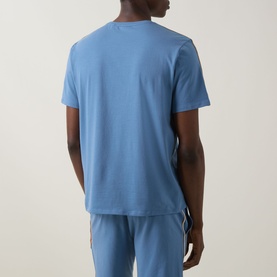 Model wearing Hugo Boss light blue cotton pyjama top, rear view, styled with matching pale blue pyjama bottoms with stripe detail.