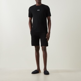 Model wearing Hugo Boss Piqu&eacute; Shorts Pyjama Set in black; short-sleeve T-shirt with logo and matching mid-rise shorts with elasticated waistband.