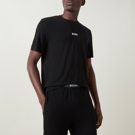 Model wearing Hugo Boss Piqu&eacute; Shorts Pyjama Set in black; short-sleeve T-shirt with chest logo and matching shorts with elasticated logo waistband