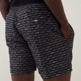 Model wearing Hugo Boss black swim shorts with allover fish print, elasticated waist, and side pockets, rear view