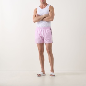 Model wearing Hugo Boss Iconic Logo Swim Shorts in bright pink with signature stripe detailing, styled with a white vest and white slider sandals