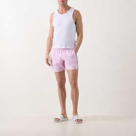 Model wearing Hugo Boss Iconic Logo Swim Shorts in Bright Pink with signature stripe detail, styled with a white vest and white sliders.