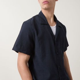 Model wearing Hugo Boss black short-sleeve camp collar shirt, styled with a white crew-neck T-shirt underneath.