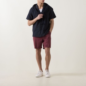 Model wearing Hugo Boss black short-sleeve hooded shirt with burgundy shorts and white trainers.