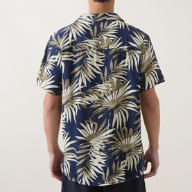 Model wearing Hugo Boss dark beige tropical print short-sleeve shirt, rear view, relaxed camp collar style in navy and beige palm leaf pattern