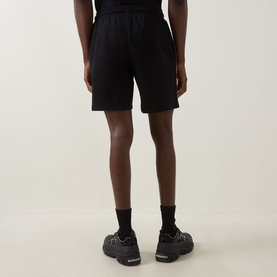 Model wearing Hugo Boss black cotton loungewear shorts, rear view, styled with black socks and dark chunky-sole trainers.