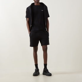 Model wearing Hugo Boss black cotton loungewear shorts with matching black t-shirt, zip hoodie, and black chunky trainers.