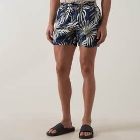 Model wearing Hugo Boss dark beige palm leaf print swim shorts with elasticated waist, styled with dark grey slider sandals.