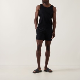 Model wearing Hugo Boss Logo Seersucker Swim Shorts in black with black vest top and brown slider sandals.