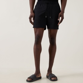 Model wearing Hugo Boss Logo Seersucker Swim Shorts in black with drawstring waist, styled with black slider sandals.