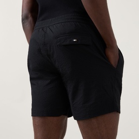 Model wearing Hugo Boss Logo Seersucker Swim Shorts in black, rear view showing flap pocket with tonal logo detail and elasticated waist.