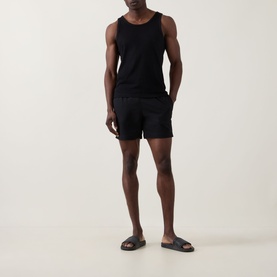 Model wearing Hugo Boss Logo Seersucker Swim Shorts in black, styled with a black vest and grey slider sandals.