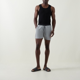 Model wearing Hugo Boss Starfish Logo Swim Shorts in grey with contrast side piping and drawstring waist, styled with a black vest and dark slides.