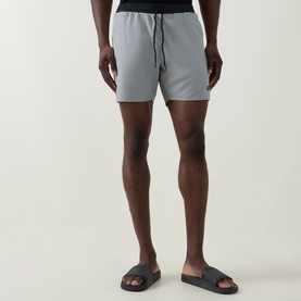 Model wearing Hugo Boss Starfish Logo Swim Shorts in grey with contrast side piping and drawstring waist, styled with navy slides
